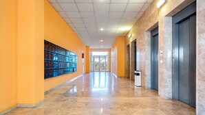 A corridor with a polished marble floor, orange walls, and a glass door at the end. - MARE INTERNUM II (La Pineda)
