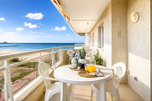 A balcony with a table, chairs, a potted plant, and a bottle of orange juice. - MARE INTERNUM I (La Pineda)