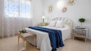 A bedroom with a bed, bedside table, lamp, and decorative wall mirrors. - MARE INTERNUM II (La Pineda)