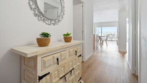 A hallway with a wooden cabinet, two potted plants, and a mirror. - BELL RACÓ Superior (La Pineda)