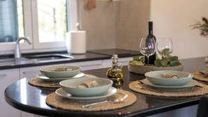 A modern kitchen with a central island, a wine bottle, and two glasses on a woven placemat. - 2-bedroom house with Hot Tube, AC, WiFi. Enjoy a cozy stay near river. (Netretić)