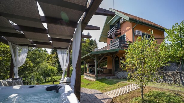 A hot tub under a pergola, a covered outdoor seating area, and a house with a balcony. - 2-bedroom house with Hot Tube, AC, WiFi. Enjoy a cozy stay near river. (Netretić)