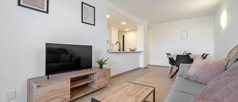 A modern living room with a flat-screen TV, wooden entertainment unit, grey sofa, and a coffee table.
