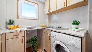 A compact kitchen with a built-in washer and dryer, a window, and a sink. - CYE V LA PINEDA (La Pineda)