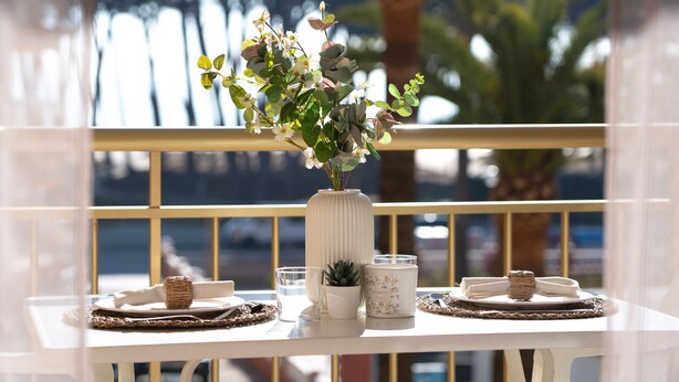 A table with a white vase, a small succulent plant, a candle, and a plate with a napkin and a small basket. - CYE V LA PINEDA (La Pineda)