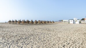 A beach with straw umbrellas and a small building with a sign. - CYE V LA PINEDA (La Pineda)