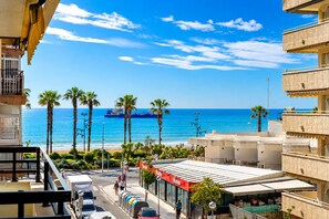 A coastal view with a blue ship, palm trees, and a building with a red sign. - Perfect for couples - A break by the sea (La Pineda)