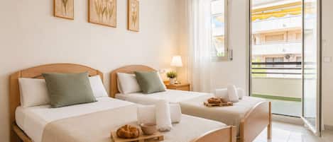 Quarto de hotel com duas camas, uma varanda e obras de arte na parede.