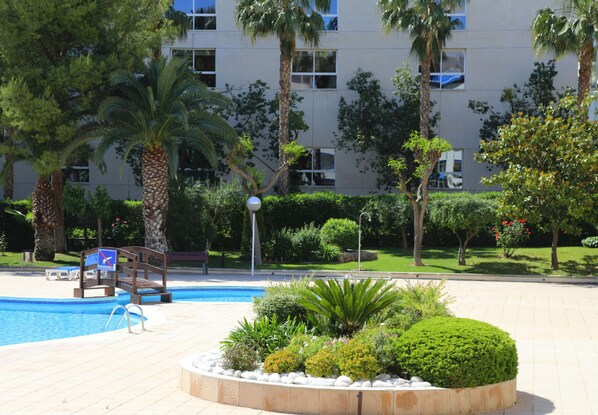 A swimming pool surrounded by palm trees and well-maintained landscaping.