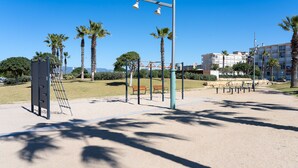Ein Park mit Trainingsgeräten, Bänken und Palmen.
