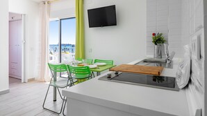 Eine moderne Küche mit Essbereich, einem an der Wand montierten Fernseher und Blick ins Freie.
