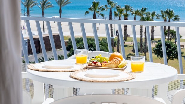 Ein Tisch mit Frühstücksangeboten und Blick auf Strand und Meer.