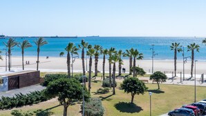 Blick auf die Küste mit Strand, Palmen und einem Parkplatz.