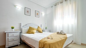A bedroom with a bed, nightstands, a dresser, and a window with curtains. - ALBENIZ Superior (La Pineda)