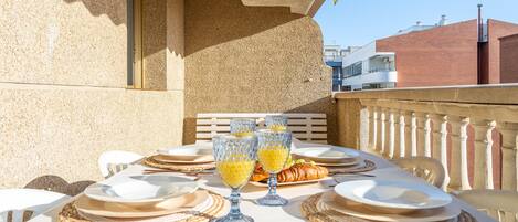 An outdoor dining area with a table set for a meal, including plates, glasses, and cutlery.