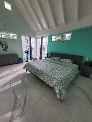 Um quarto com uma cama grande, uma cômoda e uma janela com cortinas.