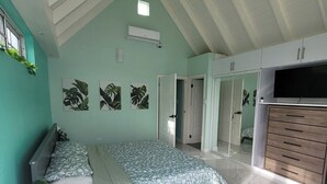 A bedroom with a bed, a desk, a wardrobe, and a TV. - Peaceful Hillside Retreat with Pool. (Ocho Rios)