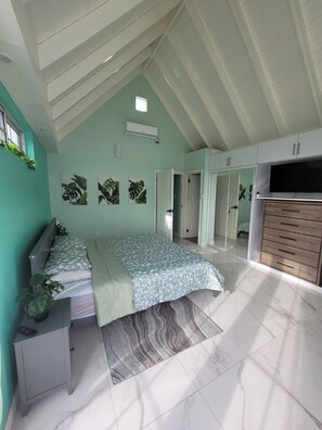 A bedroom with a bed, a desk, a wardrobe, and a TV. - Peaceful Hillside Retreat with Pool. (Ocho Rios)