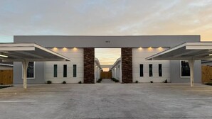 Un bâtiment moderne doté d’une entrée centrale, de deux espaces de stationnement couverts de part et d’autre, et d’un toit plat.