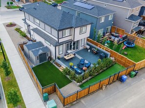 A two-story house with a deck, a fenced backyard, and a small shed.