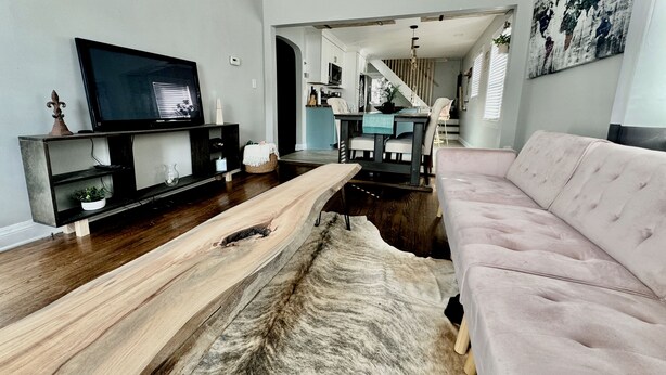 Un salon avec un téléviseur, une table basse en bois, un canapé et un tapis.