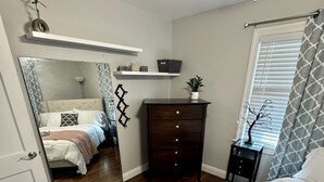 Une chambre à coucher comprenant un lit, une commode et une petite table agrémentée d’objets décoratifs.