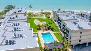 Een dakzwembad met uitzicht op de oceaan, omgeven door groen en palmbomen.