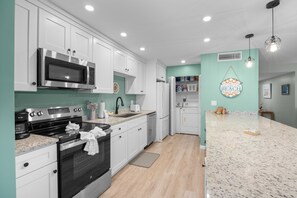 Een moderne keuken met witte kasten, roestvrijstalen apparatuur en een wand in teal kleur.