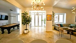 A spacious living area with a pool table, a modern chandelier, and comfortable seating.