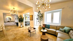 A spacious living room with a sofa, armchairs, a coffee table, and a dining area in the background.