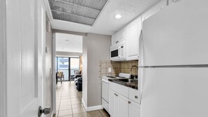 A modern kitchen with white cabinets, a microwave, and a stainless steel sink.