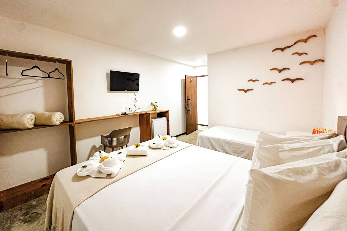 A hotel room with two beds, a desk, a TV, and a wall with bird decorations.