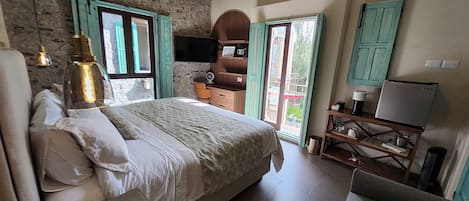 Un dormitorio con cama, escritorio, silla, televisor y ventana.