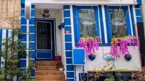 A two-story building with blue and white exterior walls, a central entrance with steps, and hanging flower baskets. - L&P MAİSON HOTEL (Istanbul)