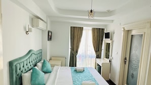 A hotel room with a large bed, a desk, a wardrobe, and a view of the city through the window. - L&P MAİSON HOTEL (Istanbul)