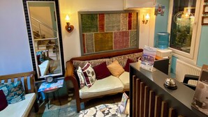 A cozy living area with a sofa, a small table, and a red chair. There is a mirror on the wall and a radiator on the floor. - L&P MAİSON HOTEL (Istanbul)