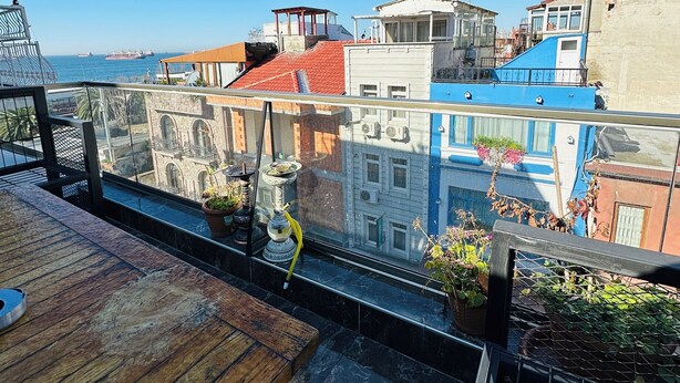 A rooftop terrace with a view of the sea and buildings. - L&P MAİSON HOTEL (Istanbul)