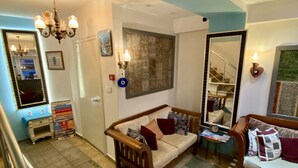 A spacious living area with a wooden sofa, a red chair, a dining table, and a chandelier. - L&P MAİSON HOTEL (Istanbul)