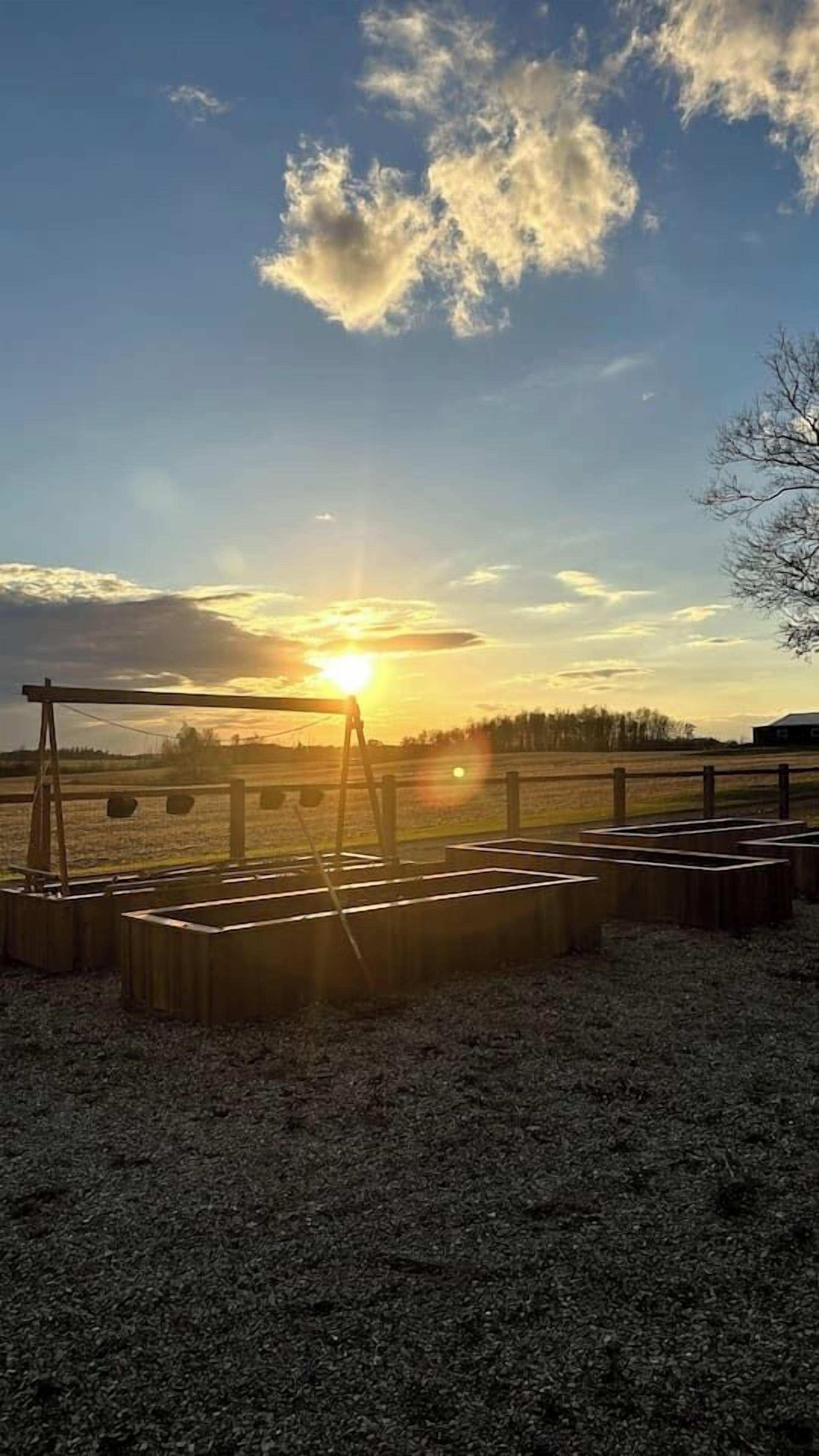 A sunset over a rural landscape with a wooden structure in the foreground.