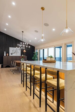 A modern kitchen with a bar area, pendant lighting, and a large window.