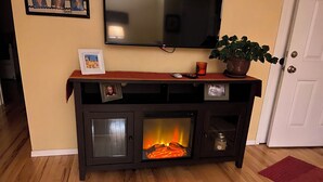 A living room with a fireplace, a television mounted on the wall, and a door in the background.