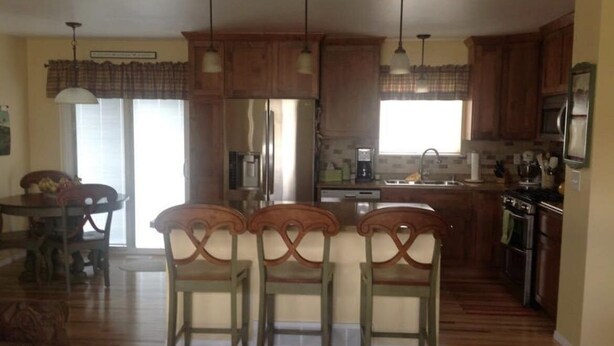 A spacious kitchen with wooden cabinets, a dining area with a table and chairs, and a large window providing natural light.