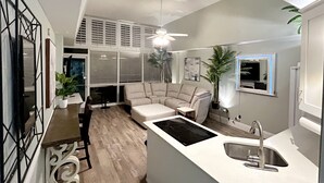 Una cocina moderna con una isla integrada, un área de comedor con sofá y un ventilador de techo.
