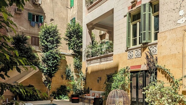 A courtyard with a pool, outdoor seating, and a building with balconies.