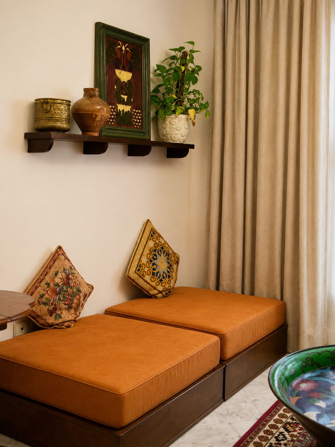 Una habitación con sofá, estanterías decorativas, una planta en maceta y una alfombra estampada.