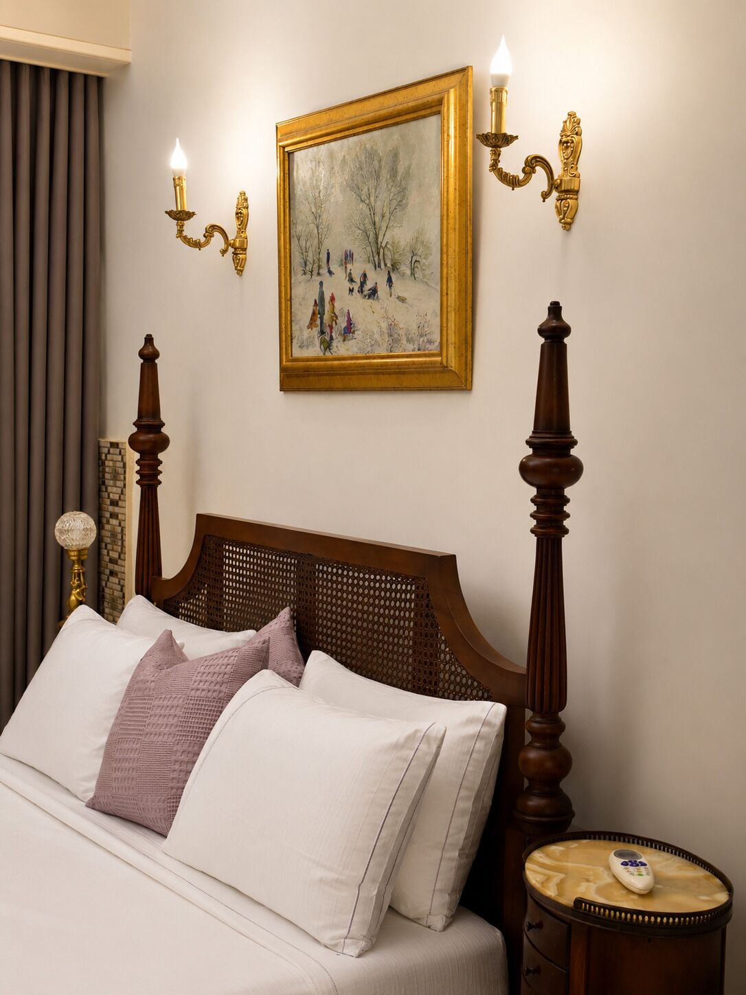 Une chambre d’hôtel avec un lit, un tableau, des appliques murales et une table de chevet avec une télécommande.