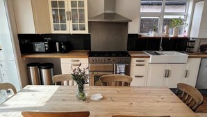 Una cocina con armarios de madera, estufa, horno y una mesa de comedor con sillas.