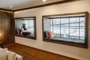 A room with a wooden floor, a sofa, and two windows with wooden frames. - The Folkster House Chiangkhan (Chiang Khan)