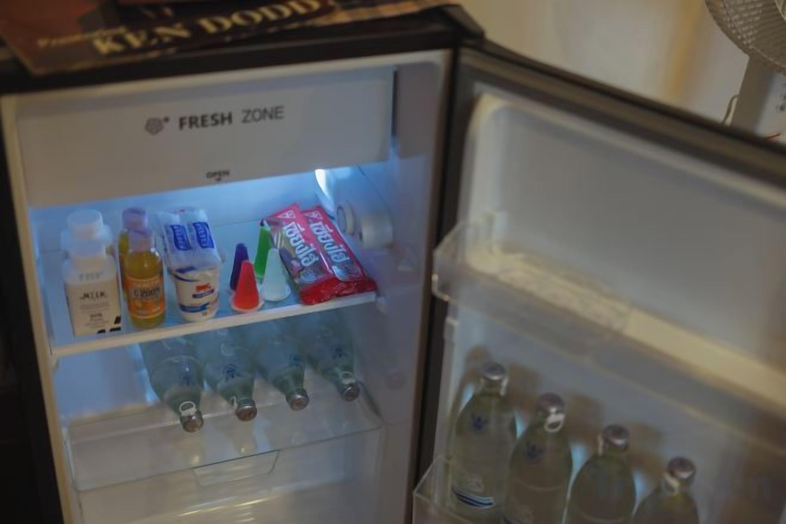 Un réfrigérateur doté d’un distributeur d’eau et d’une étagère contenant diverses boissons.