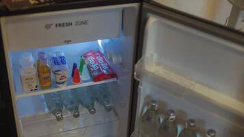 Un refrigerador con dispensador de agua y un estante con diversas bebidas.